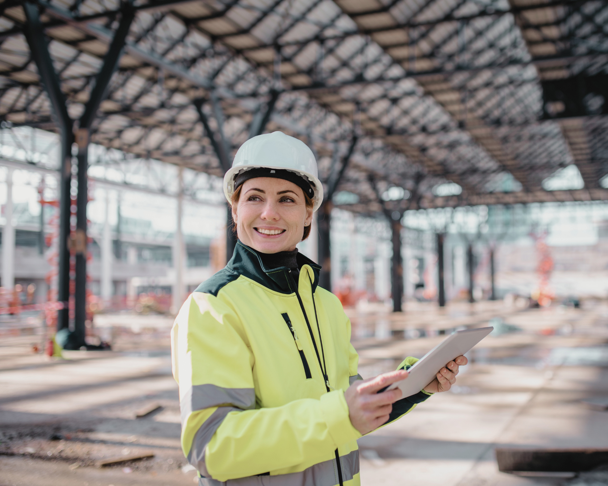 Weibliche Person mit Schutzhelm und Klemmbrett auf einer Großbaustelle