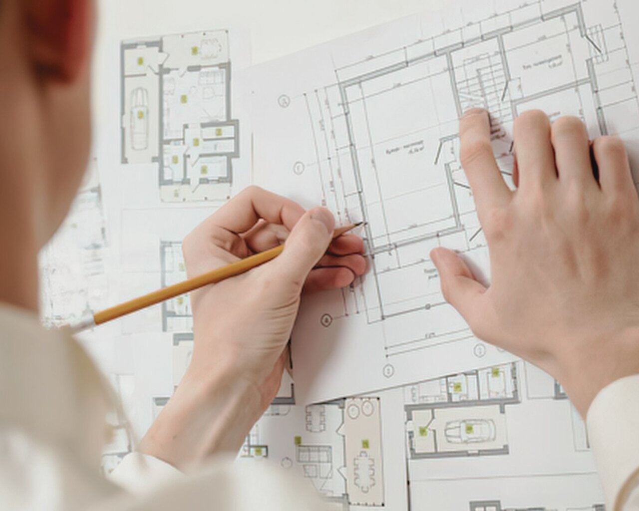 Hände fertigen eine technische Architekturzeichnung mit einem Stift an