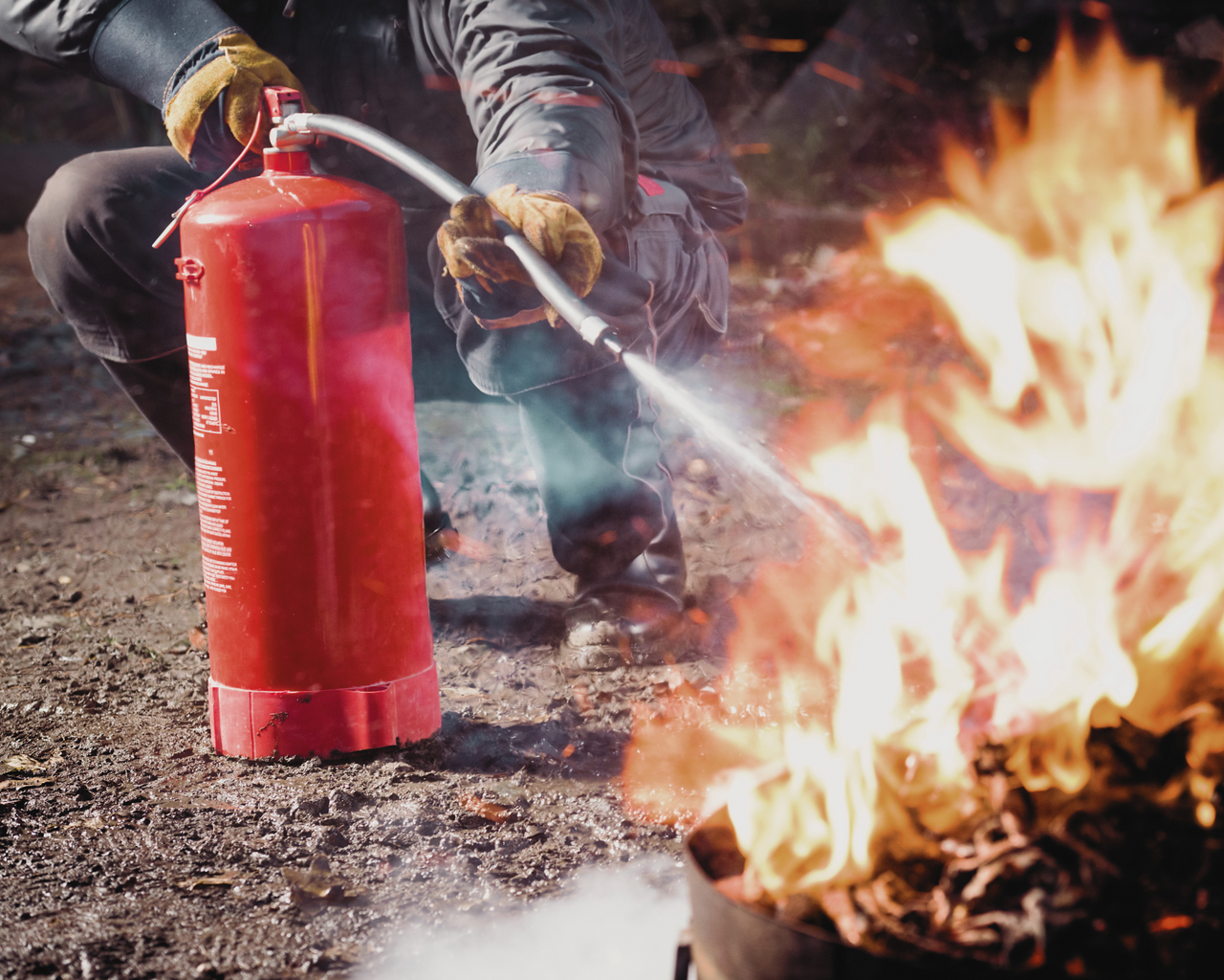 Person löscht Feuer mit Feuerlöscher