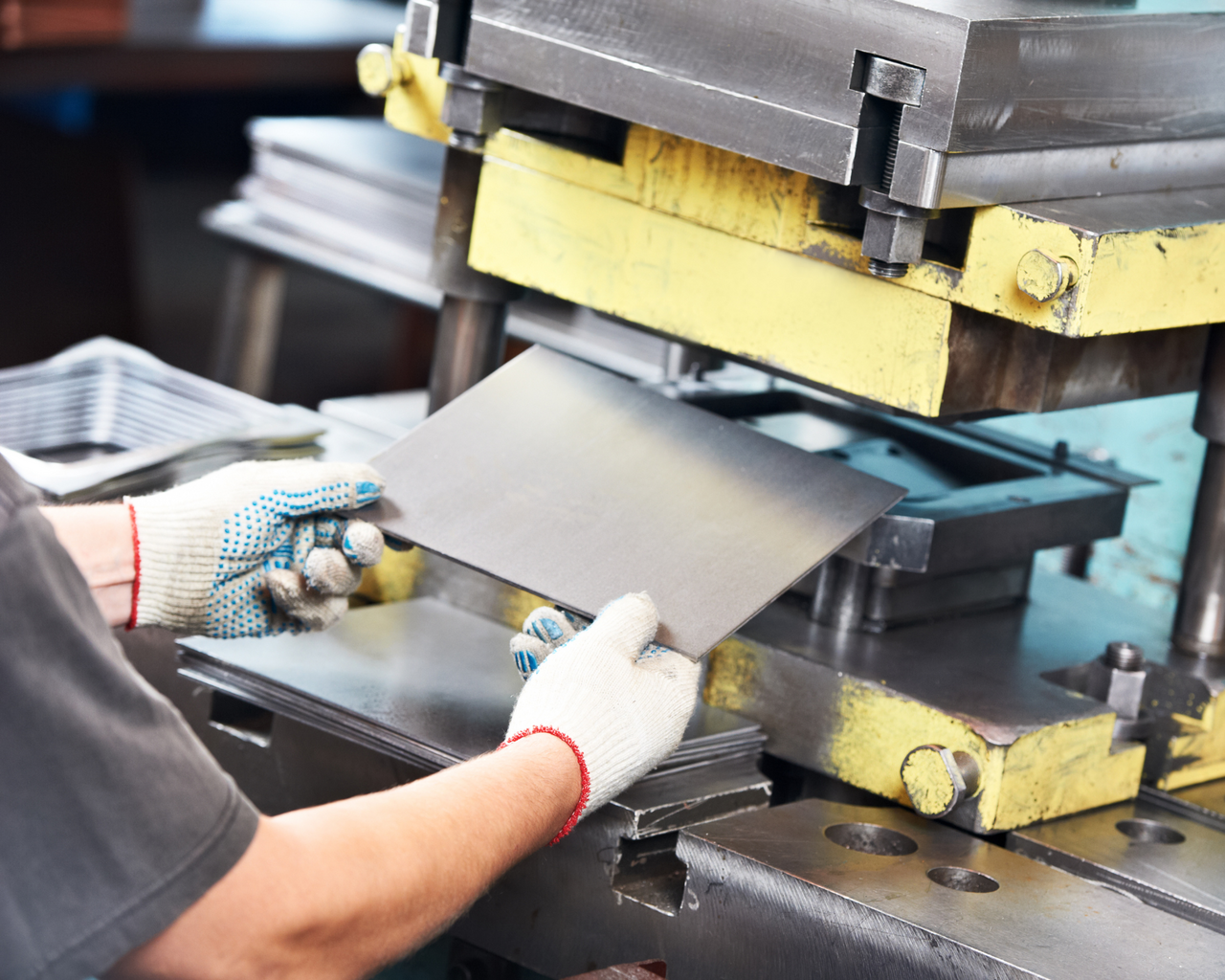 Person schiebt Metallblech in einer Presse