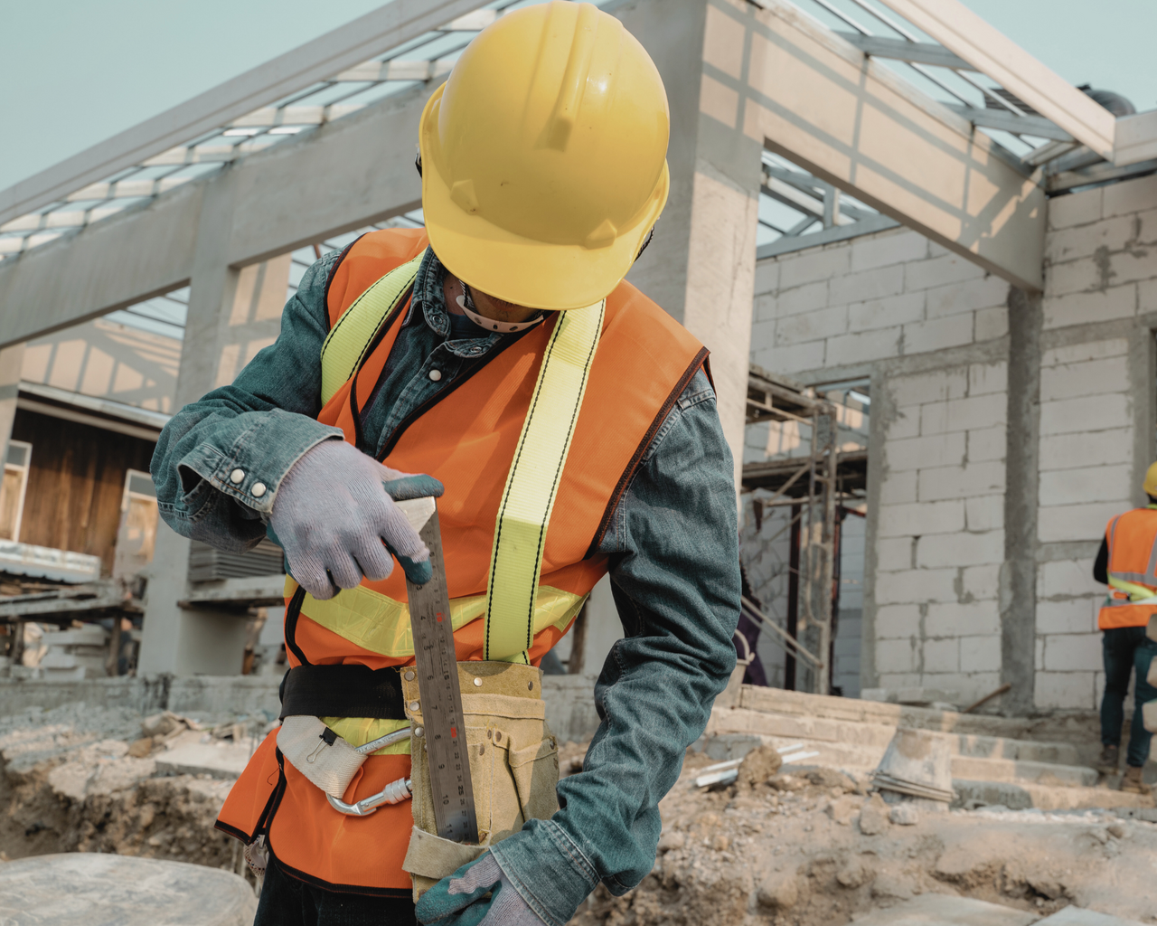 Mann in Sicherheitskleidung mit Helm und Warnweste auf Baustelle